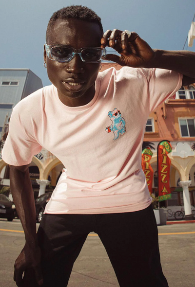 A man wearing a pink Riot Society t-shirt and sunglasses