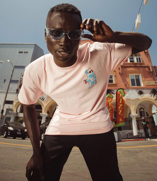 A man wearing a pink Riot Society t-shirt and sunglasses