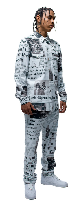 A man wearing an allover newsprint button up and pants done by Karl Kani