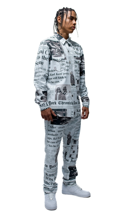 A man wearing an allover newsprint button up and pants done by Karl Kani