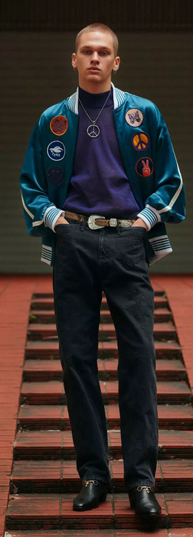 A man wearing a Needles jacket with peace prints allover it and black pants