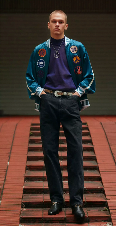 A man wearing a Needles jacket with peace prints allover it and black pants