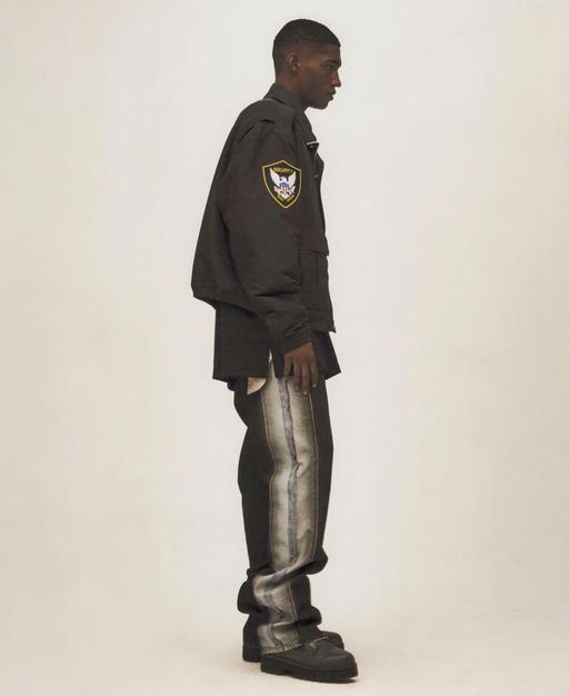 A man wearing a Heron Preston outfit featuring a coaches jacket and baggy jeans