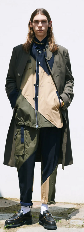A man wearing a green and brown Sacai jacket with black loafers
