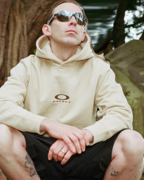 A man wearing Oakley sunglasses and branded hoodie