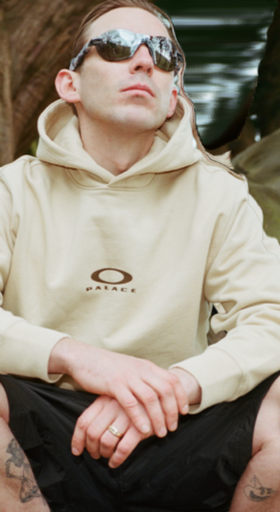 A man wearing Oakley sunglasses and branded hoodie
