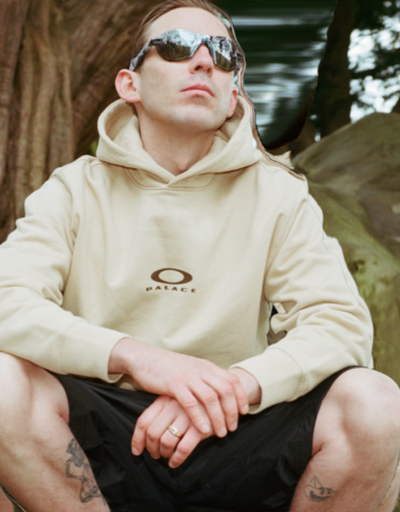 A man wearing Oakley sunglasses and branded hoodie