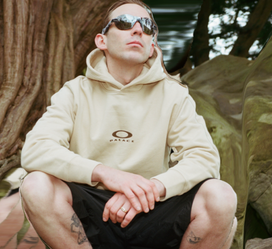 A man wearing Oakley sunglasses and branded hoodie