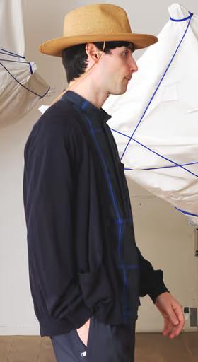 A man wearing a Nonnative navy blue sweater, blue button up and brown flat brimmed hat