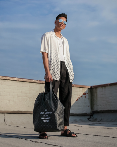 A man wearing a Fragment x Louis Vutton button up and black pants