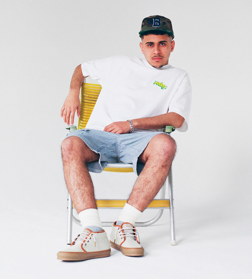 A man sitting and wearing a Bodega t-shirt with jean shorts