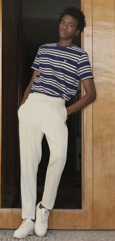 A man wearing a Fila outfit with a striped t-shirt and white pants
