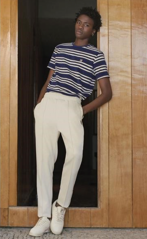 A man wearing a Fila outfit with a striped t-shirt and white pants