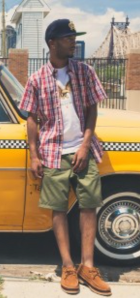 A man wearing a Acapulco Gold plaid button up with a white t-shirt and green shorts