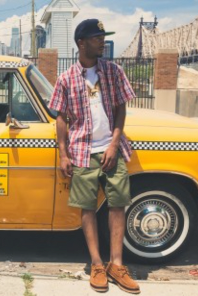 A man wearing a Acapulco Gold plaid button up with a white t-shirt and green shorts