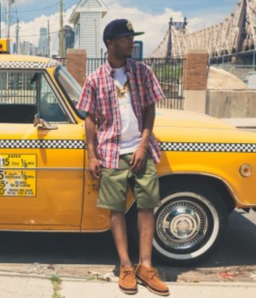 A man wearing a Acapulco Gold plaid button up with a white t-shirt and green shorts