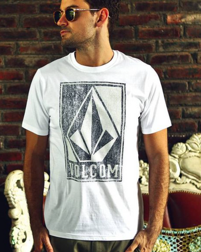A man wearing a Volcom logo icon t-shirt in white and sunglasses