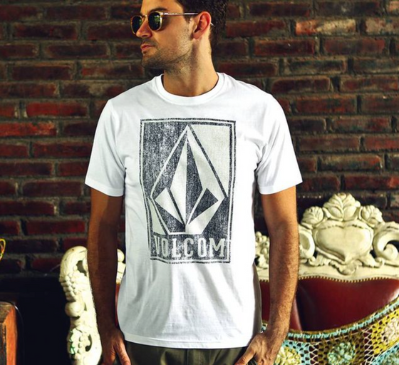 A man wearing a Volcom logo icon t-shirt in white and sunglasses