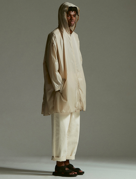 A man wearing an Element outfit with a long beige raincoat and beige pants