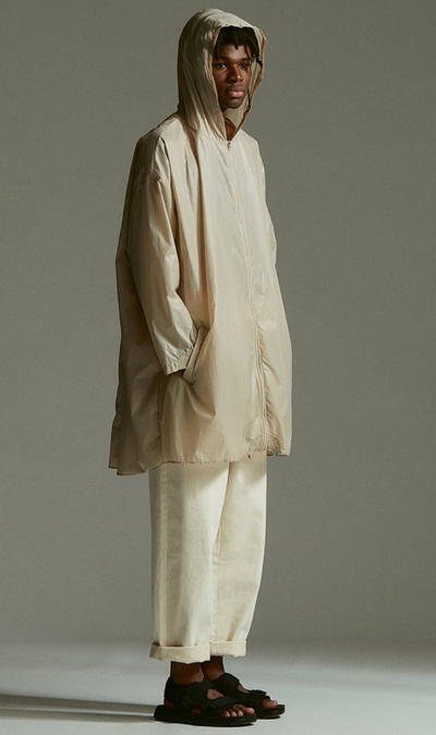 A man wearing an Element outfit with a long beige raincoat and beige pants