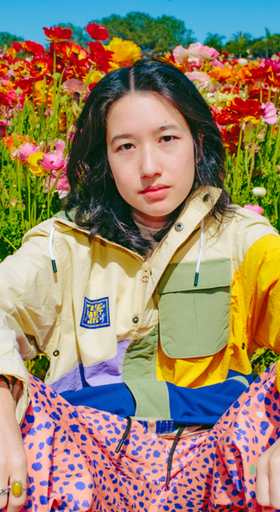 A womman wearing The Quiet Life outfit sitting amidst a bed of roses