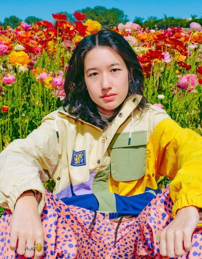 A womman wearing The Quiet Life outfit sitting amidst a bed of roses