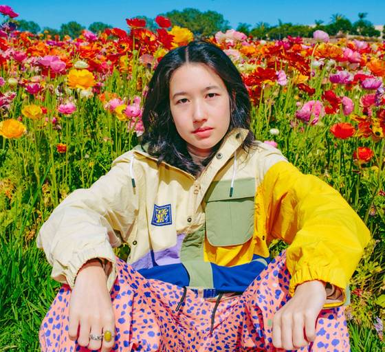 A womman wearing The Quiet Life outfit sitting amidst a bed of roses