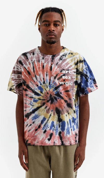 A man wearing a tie dye Goodhood t-shirt and green pants
