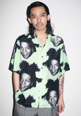 A man wearing a Wacko Maria Jean-Michel Basquiat all over print button up t-shirt