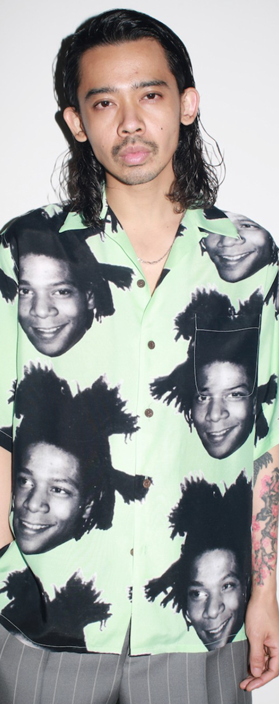 A man wearing a Wacko Maria Jean-Michel Basquiat all over print button up t-shirt