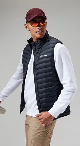A man wearing a Berghaus vest, long-sleeve and a red hat