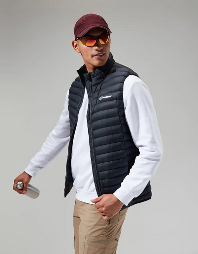 A man wearing a Berghaus vest, long-sleeve and a red hat