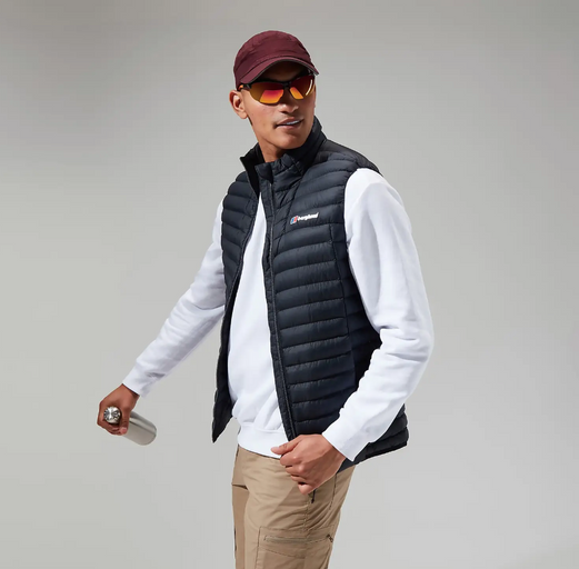 A man wearing a Berghaus vest, long-sleeve and a red hat