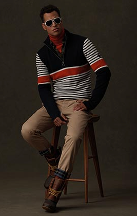 A man sitting wearing a Brooks Brothers outfit featuring a striped long-sleeve, Khaki's and sunglasses