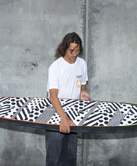 A man holding a surf board wearing a Vissla white t-shirt