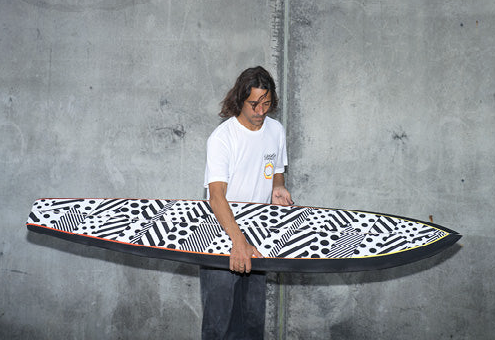 A man holding a surf board wearing a Vissla white t-shirt