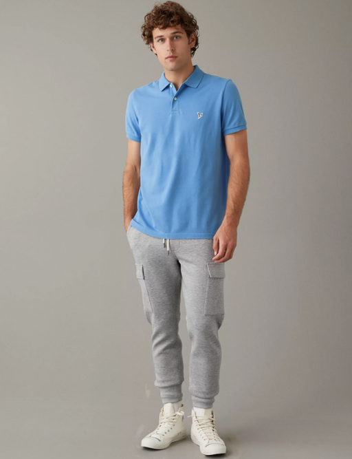 A man wearing a blue American Eagles Outfitters collared shirt with grey sweats
