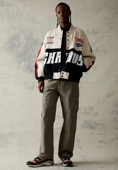 A man wearing a PacSun racing coat with green pants
