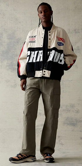 A man wearing a PacSun racing coat with green pants