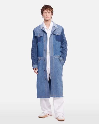 A man wearing a denim overcoat by Marine Serre and white pants and button ups