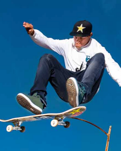 A man skateboarding while wearing green Etnies shoes