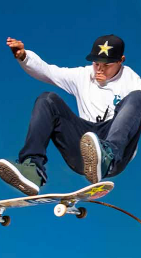 A man skateboarding while wearing green Etnies shoes
