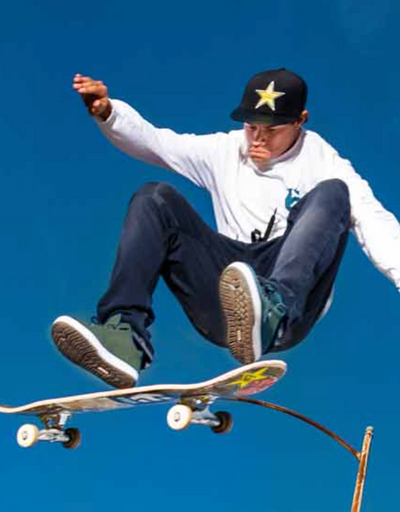A man skateboarding while wearing green Etnies shoes