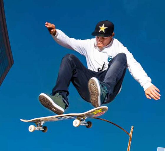 A man skateboarding while wearing green Etnies shoes