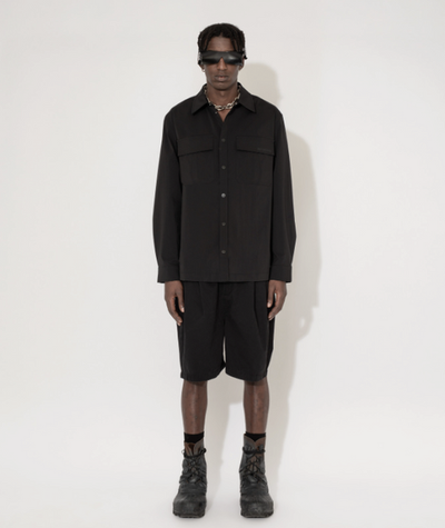 A man wearing a Han Kjøbenhavn black shirt and shorts