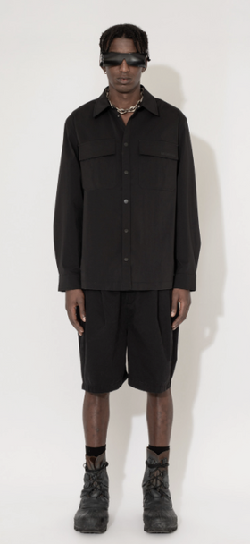 A man wearing a Han Kjøbenhavn black shirt and shorts