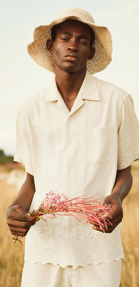 A man wearing a CMMN SWDN cream button up with a farmers hat