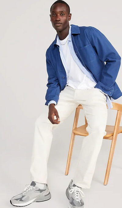 A man sitting and wearing a denim Old Navy over shirt with white pants and grey shoes