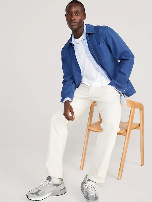 A man sitting and wearing a denim Old Navy over shirt with white pants and grey shoes