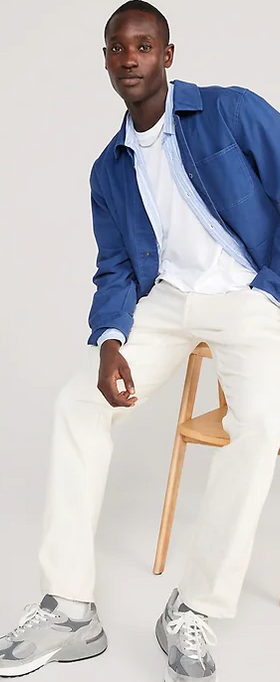 A man sitting and wearing a denim Old Navy over shirt with white pants and grey shoes